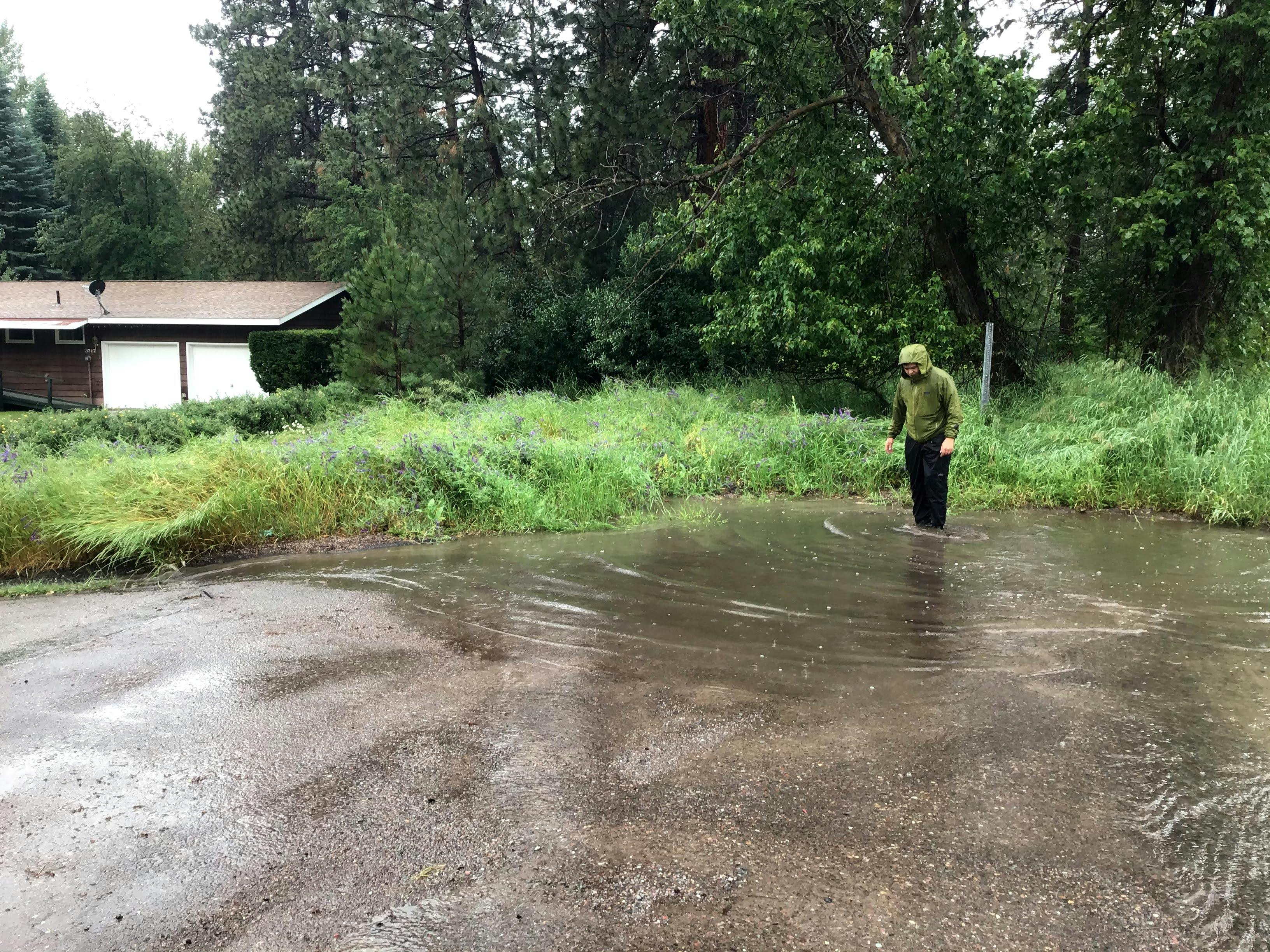 Image of a man standing in a pool of water caused by a clogged storm drain