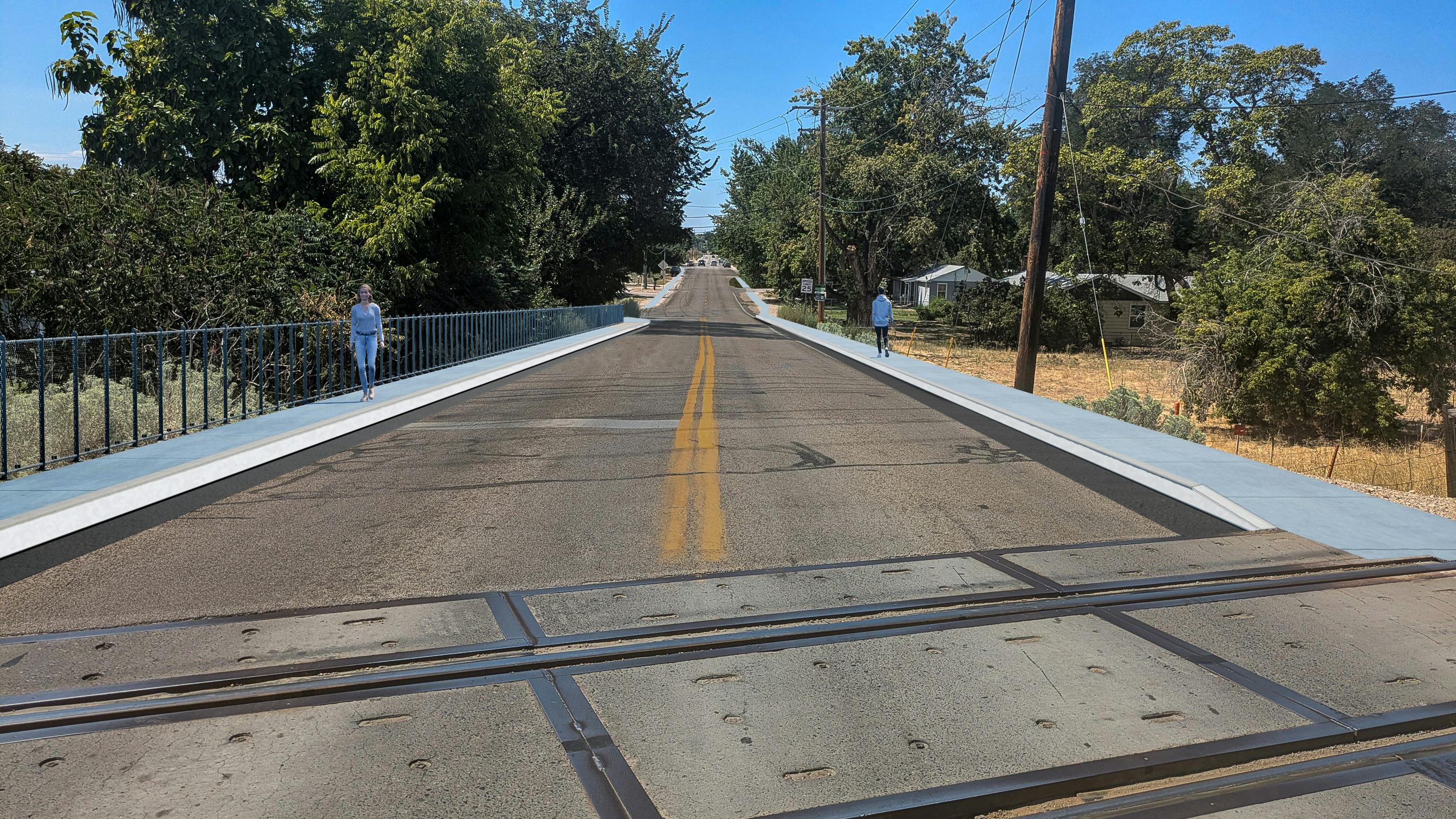 Victory Road at the railroad tracks with sidwalk on both sides of street and a pedestrian railing.