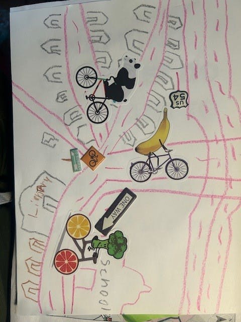a child's drawing with crayon and bike stickers showing a ride to school