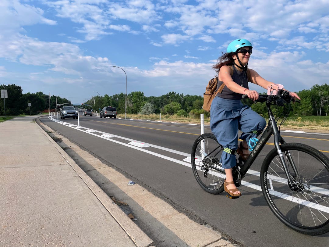 A bicyclist riding in a bike lane separated from the road with plastic curbs and posts