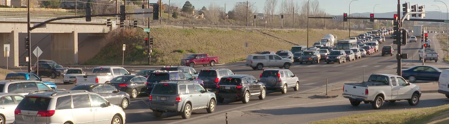 Multiple lanes of traffic are stopped at santa fe and mineral, waiting at red lights under a clear sky.