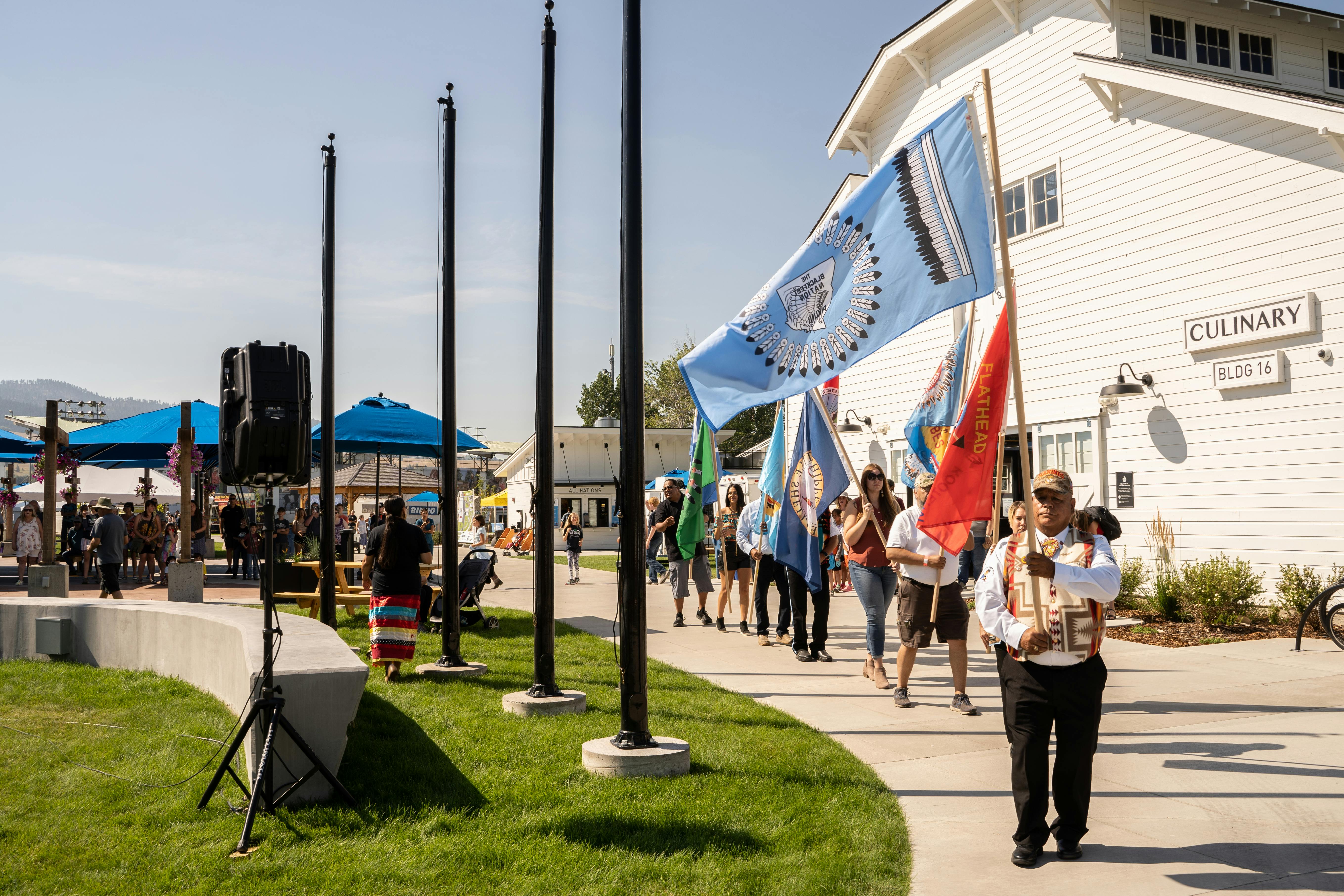 The Tribal Nations walk to the flagpoles in the Historic Plaza to raise their flags at the Fair.