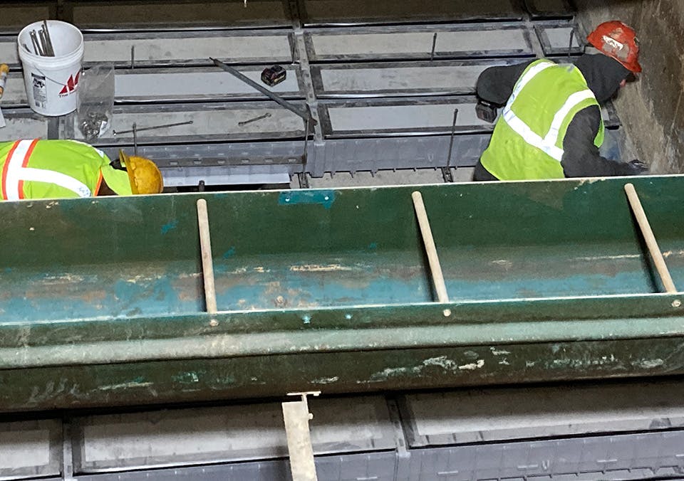 Crew workers install the underdrain in Filter 5 inside the filter building.