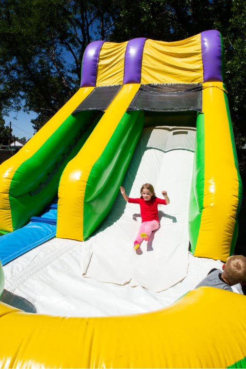 Girl sliding down a bounce house slide.png