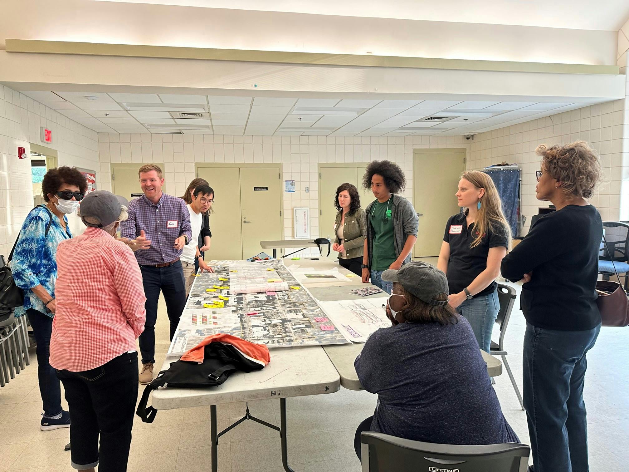 Three project team members are gathered around a map of Downtown Chapel Hill with seven community members talking 