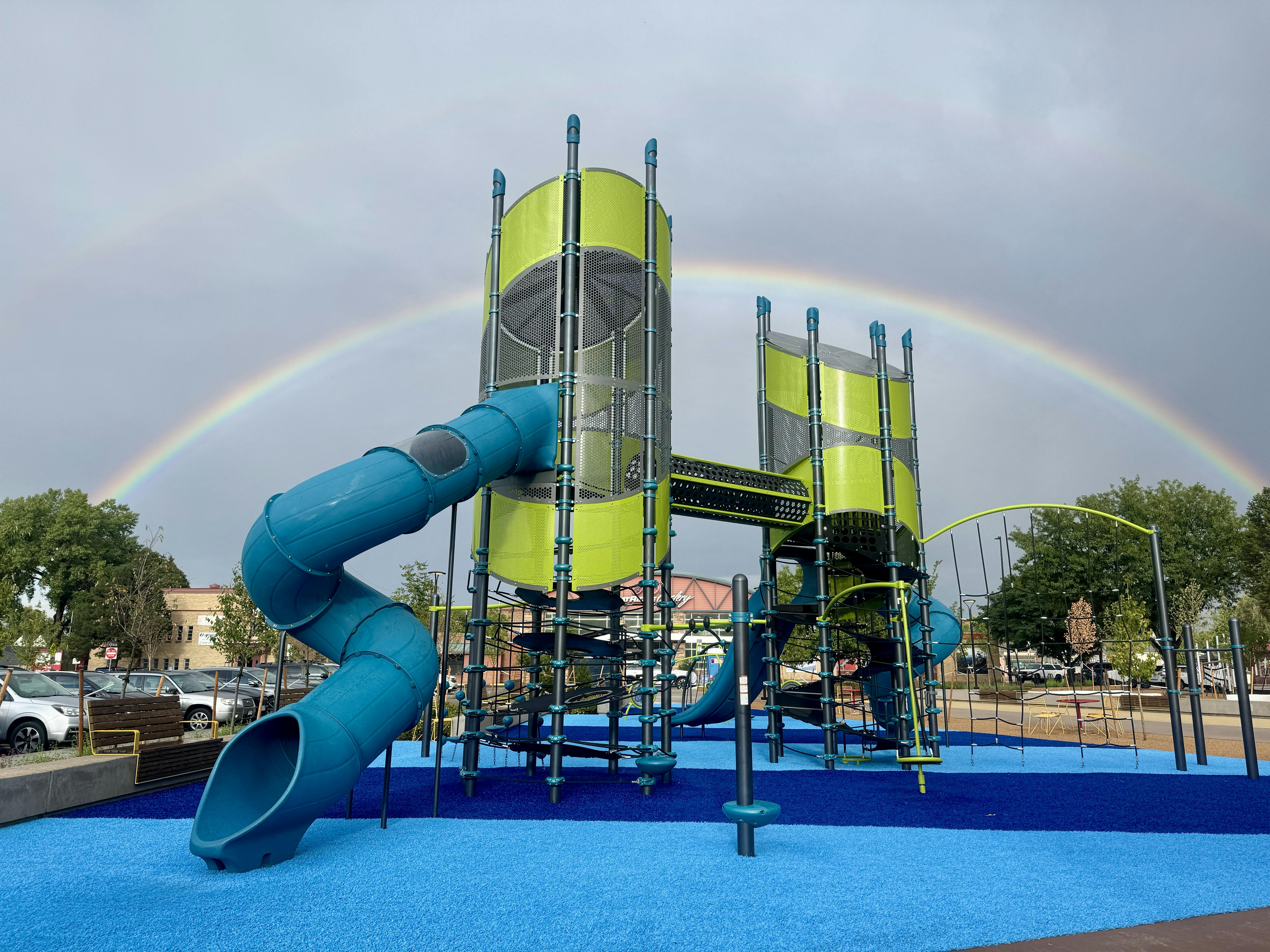 Picture of playground at Green at 38th with rainbow above and behind it