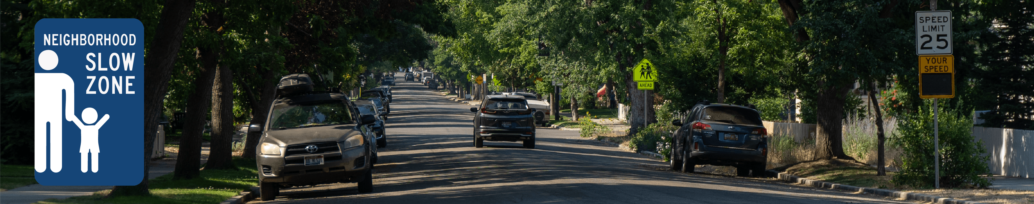 A tree-lined street in a Boise's North End with parked cars and a "SLOW ZONE" logo on the left-hand side.