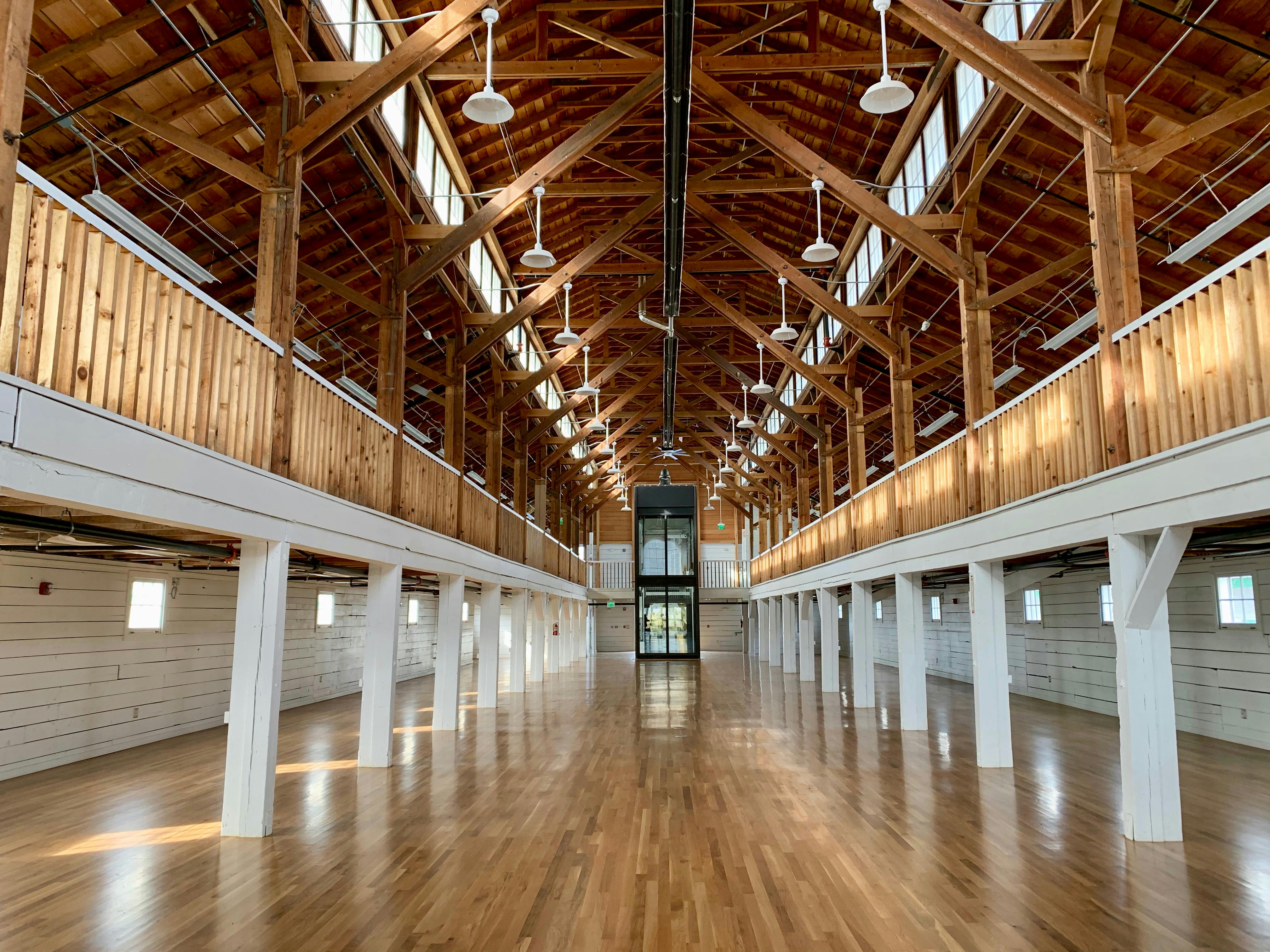 Inside of Fairgrounds Commercial Building showing polished wood floors and light streaming through the windows.