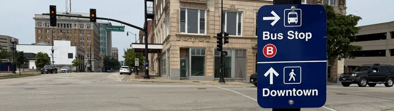 Downtown street scene in Waukegan with wayfinding signs pointing people to the bus stop and downtown. 