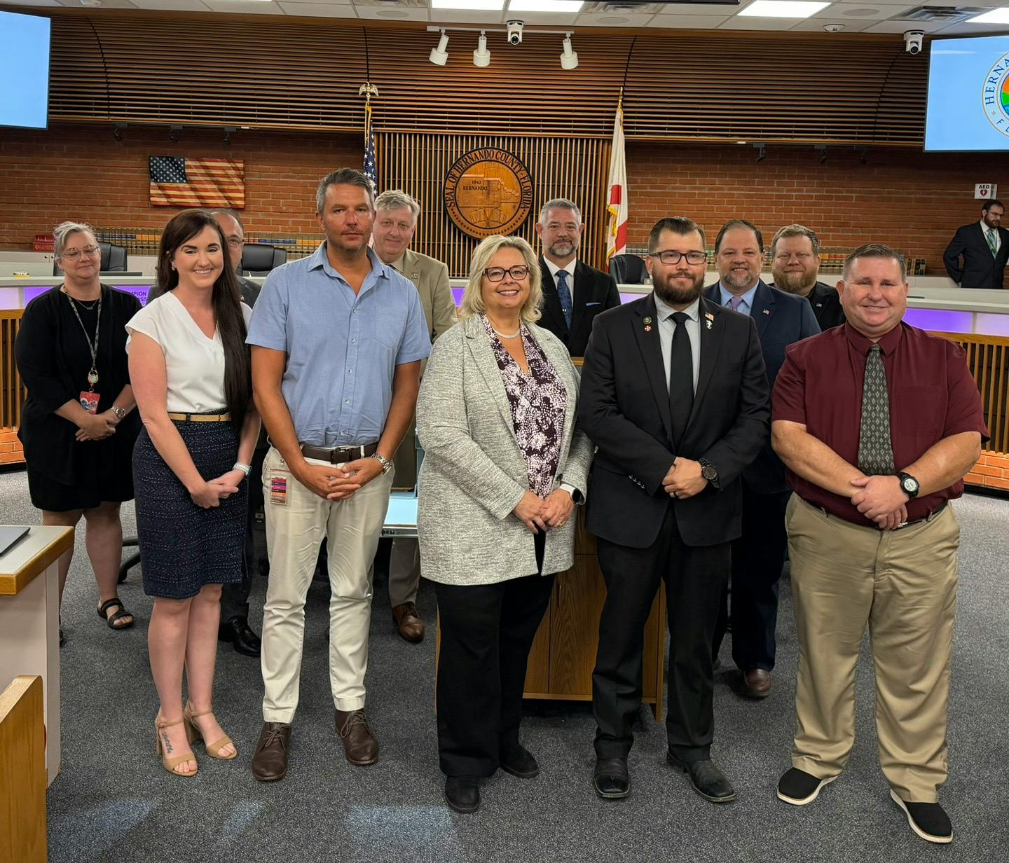 group smiling at county commissioner meeting