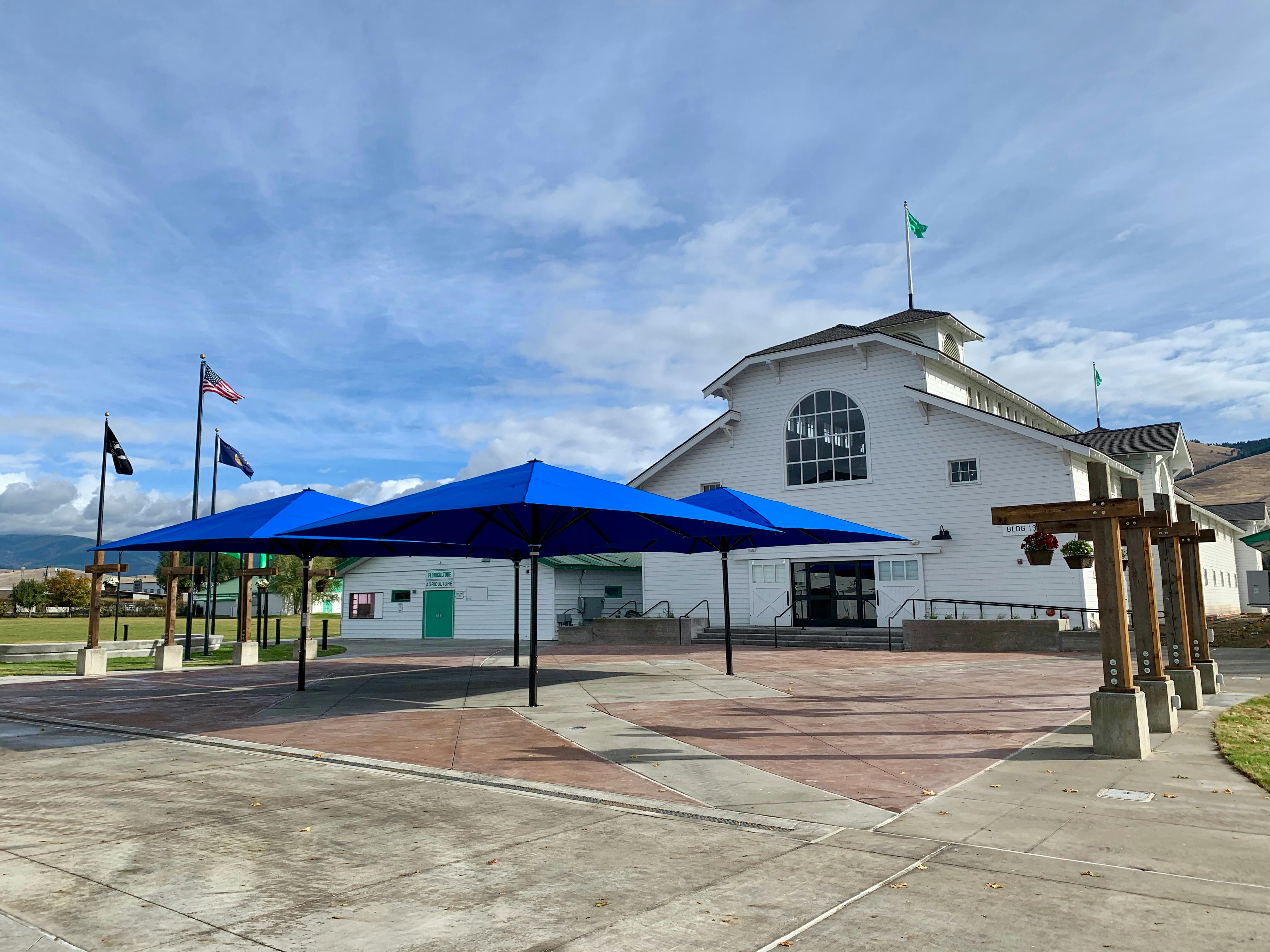 The Commercial Building and the Historic Plaza on a sunny day with a blue sky. Blue umbrellas are open.