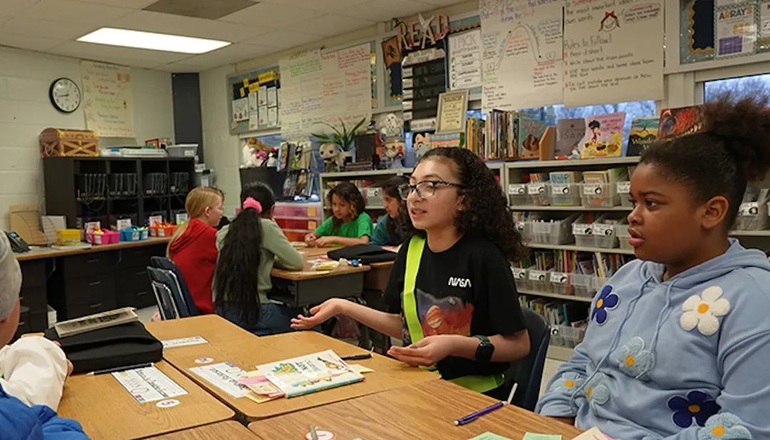 Students in classroom at table talking
