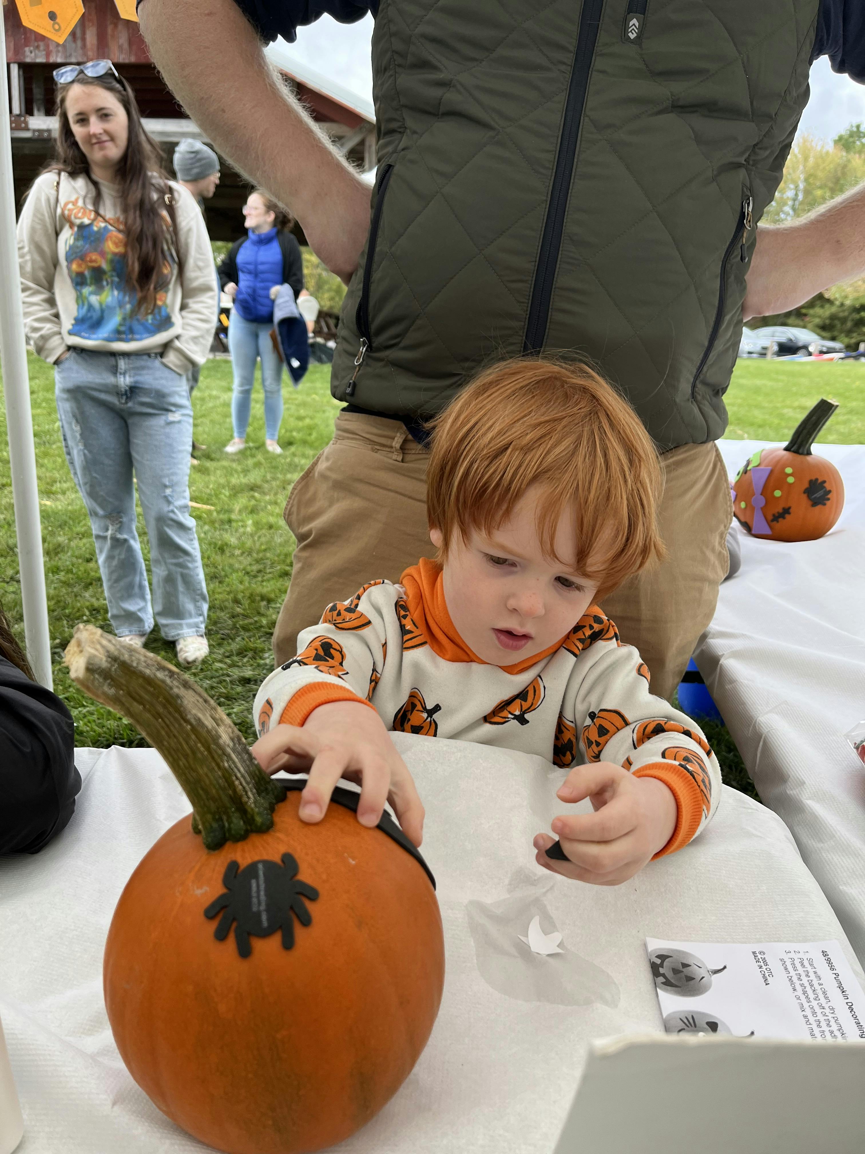 Young lad displaying his pumpkin decorations. Check out his outfit! Cute!