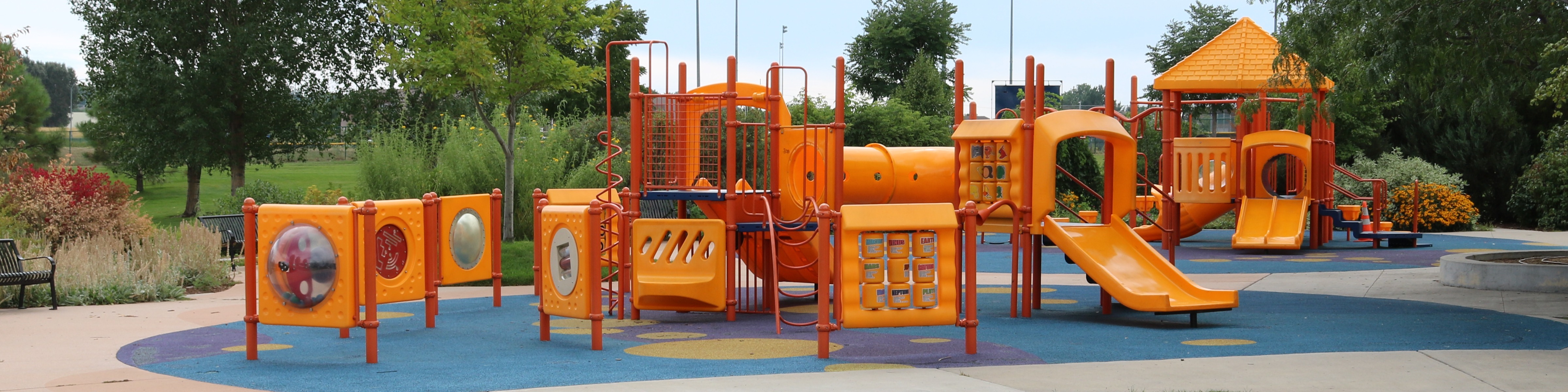 A yellow and red playground with trees in the background