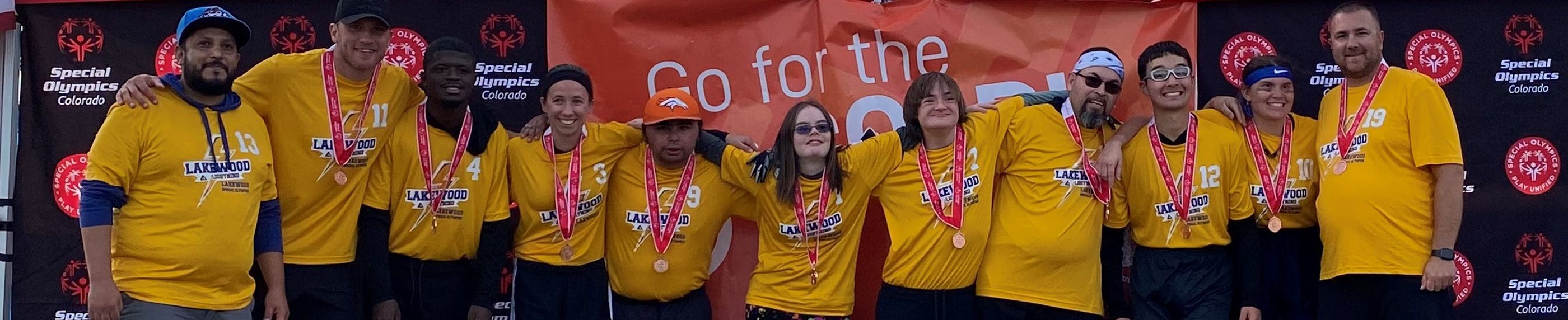 Shows a group of Special Olympics participants with their medals at an Special Olympics event.