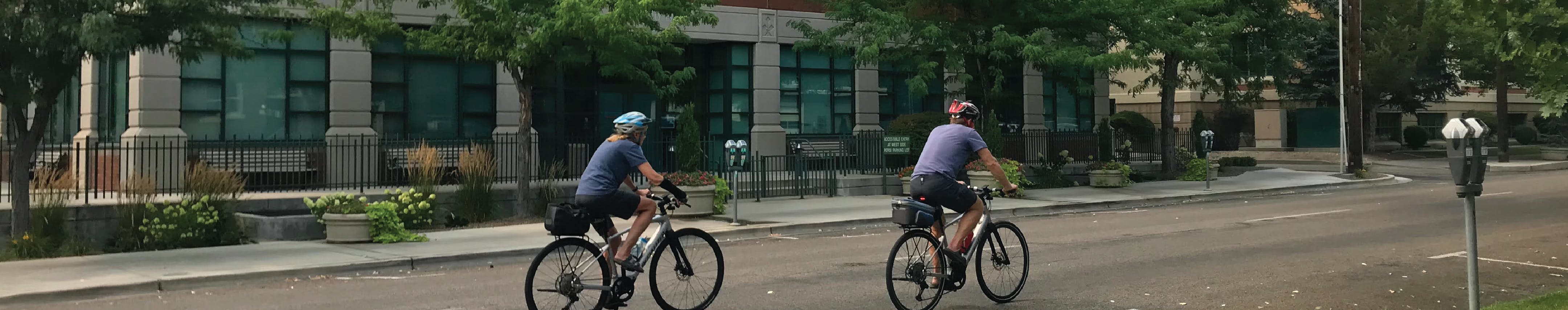 Two bicyclists biking on street.