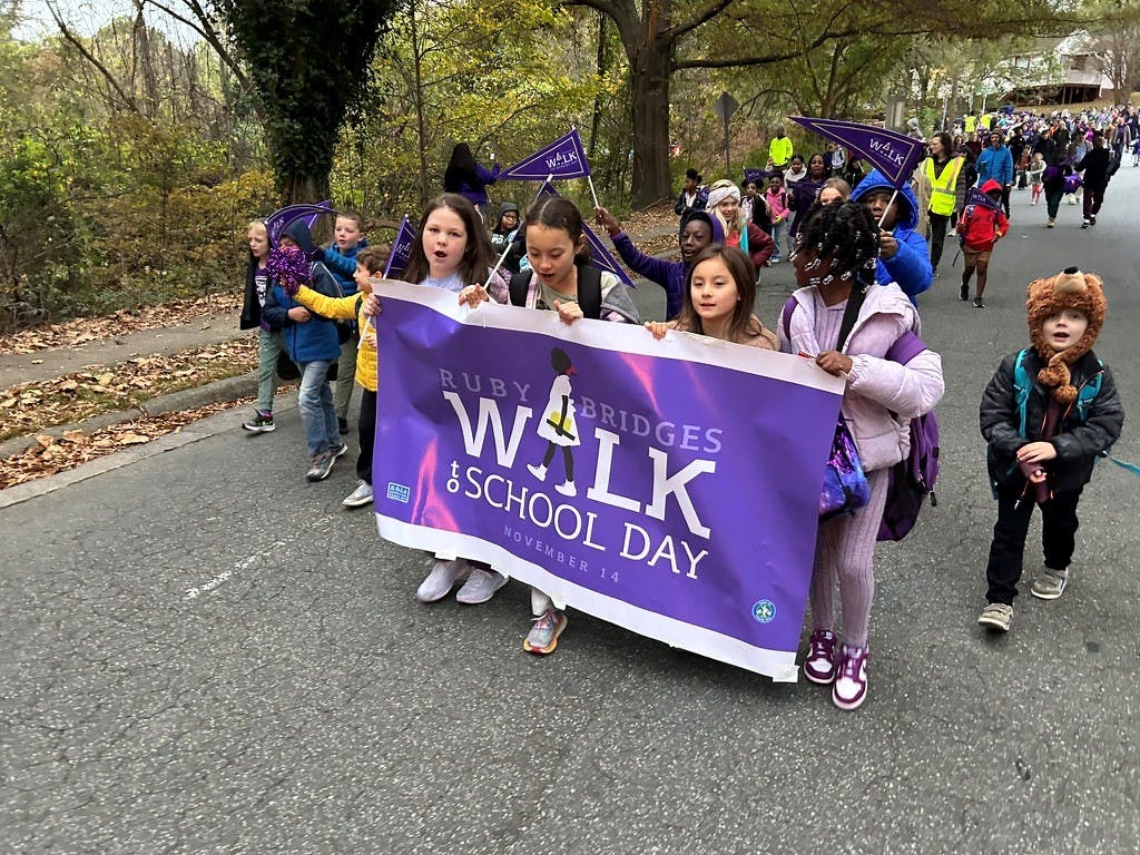 Kids walking and holding a banner that says "Ruby Bridges Walk to School Day"