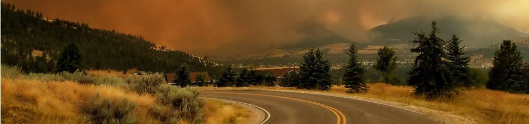 Orangey image of Seeley Lake during wildfire season, with heavy smoke hovering over the mountains