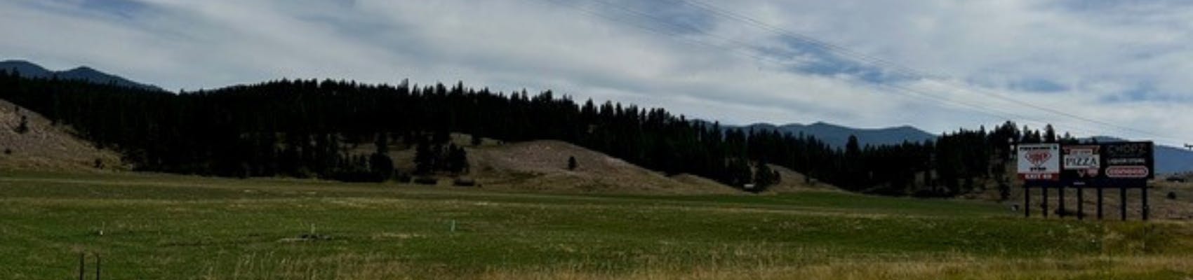 Area where proposed Elk Valley Ranch Subdivision would be constructed. Green grasses with mountains and billboard on right