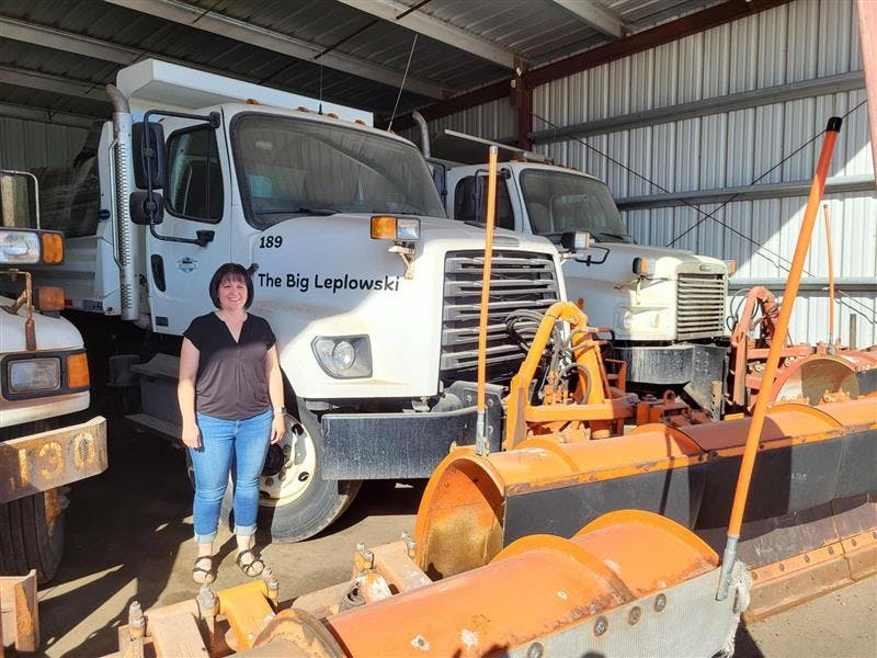 Image of a woman standing in front of a snowplow named "Big Leplowski"