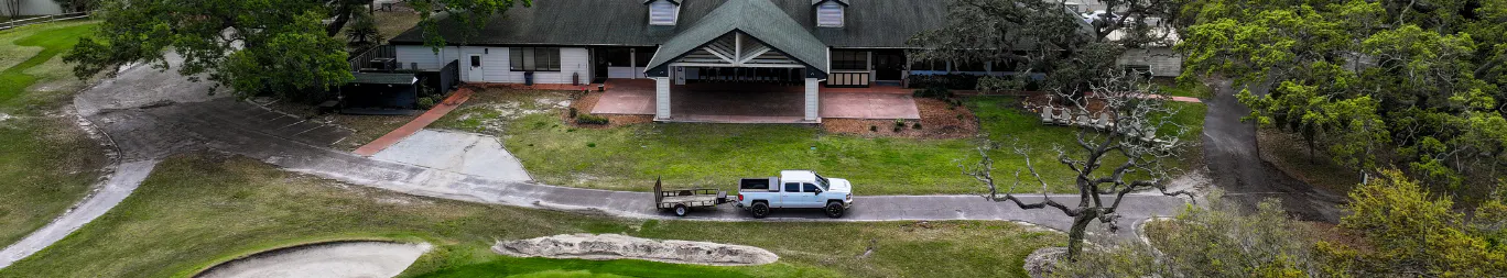 Aerial shot of golf club, truck driving along road and golf course in Dunedin