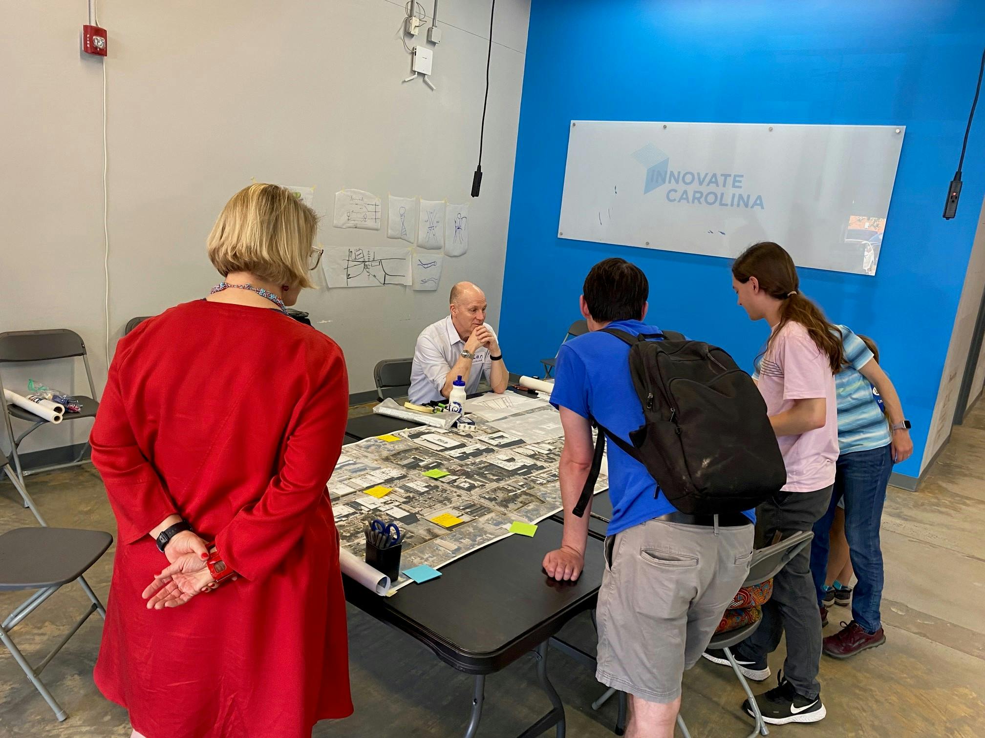 Four community members are standing around a large map of Downtown Chapel Hill placing post-it notes.