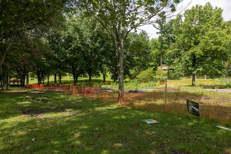 A closer view of the playground construction site, it is an empty field surrounded by an orange mesh fence.