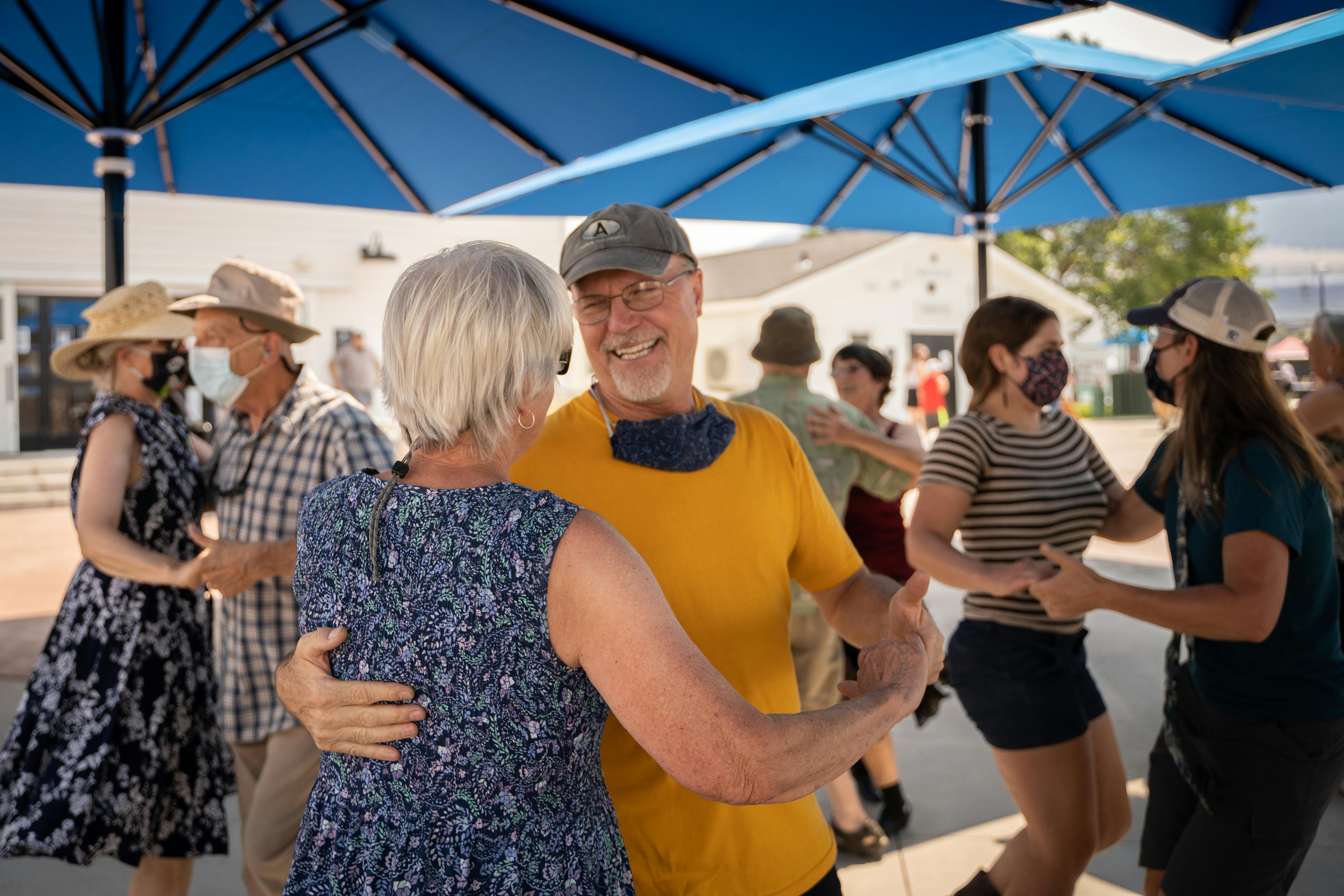 Couples dance on a sunny day at the fair.