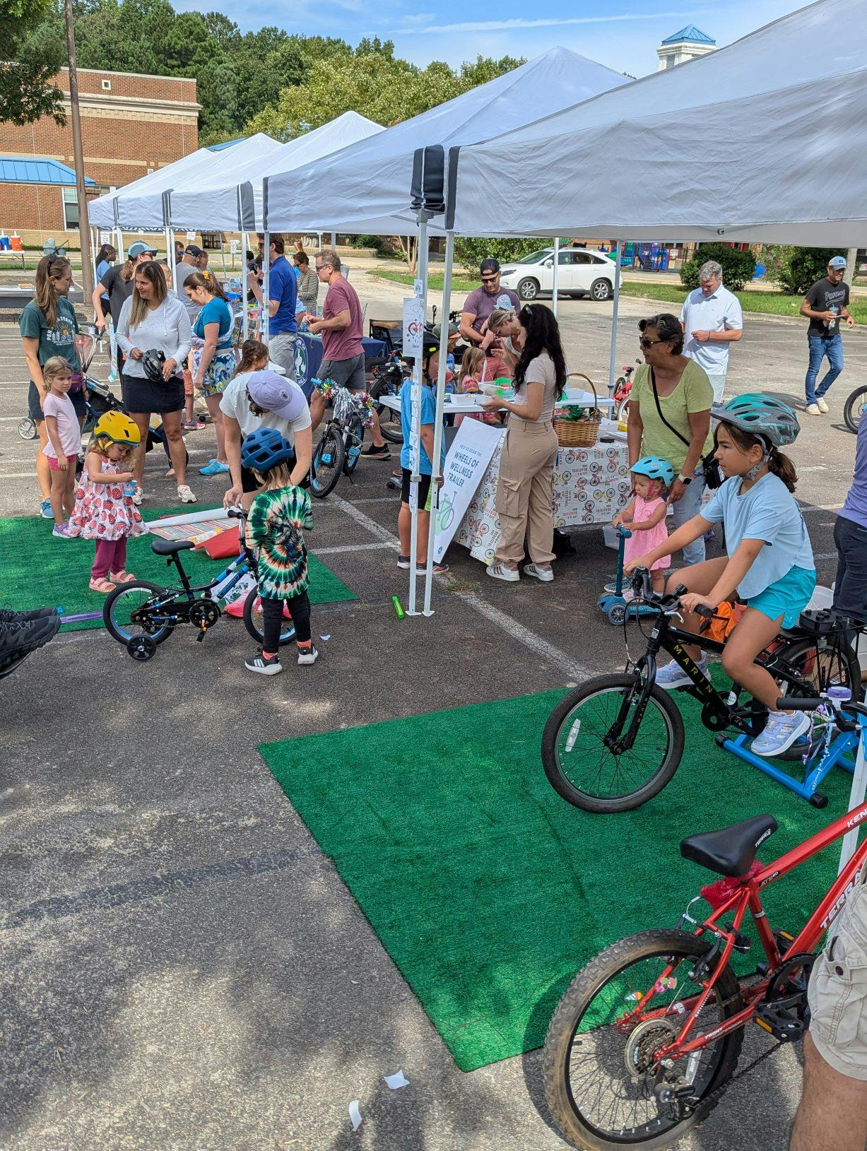 Kids and adults around outdoor tents with bikes and crafts