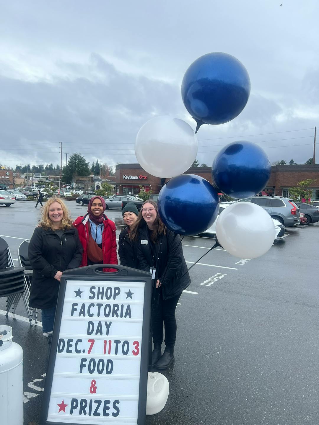 Photo of 4 women behind sign and balloons celebrating "shop factoria"