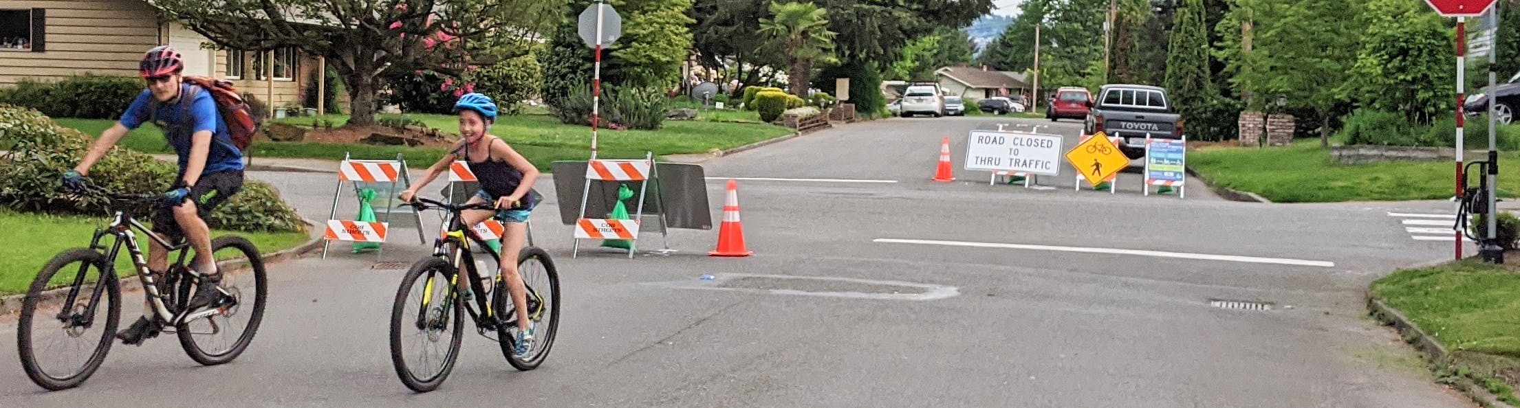 Two people riding bicycles on a Healthy Street closed to through vehicle travel.