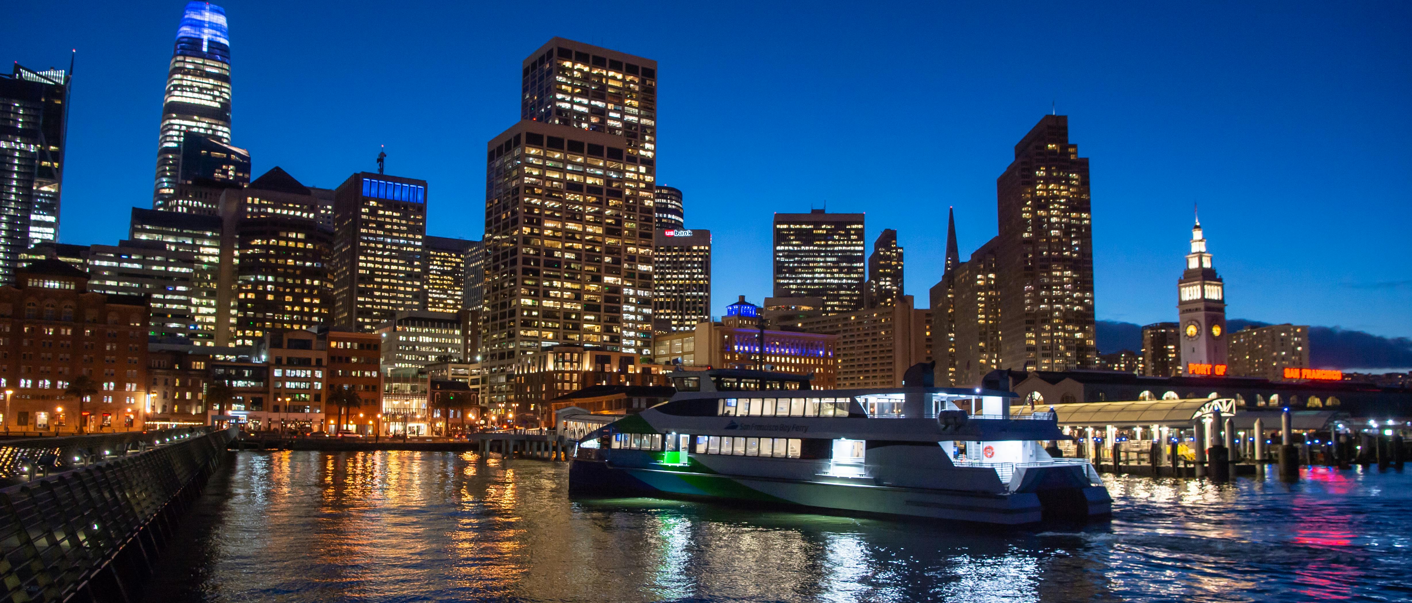 Ferry at night in front of city skyline