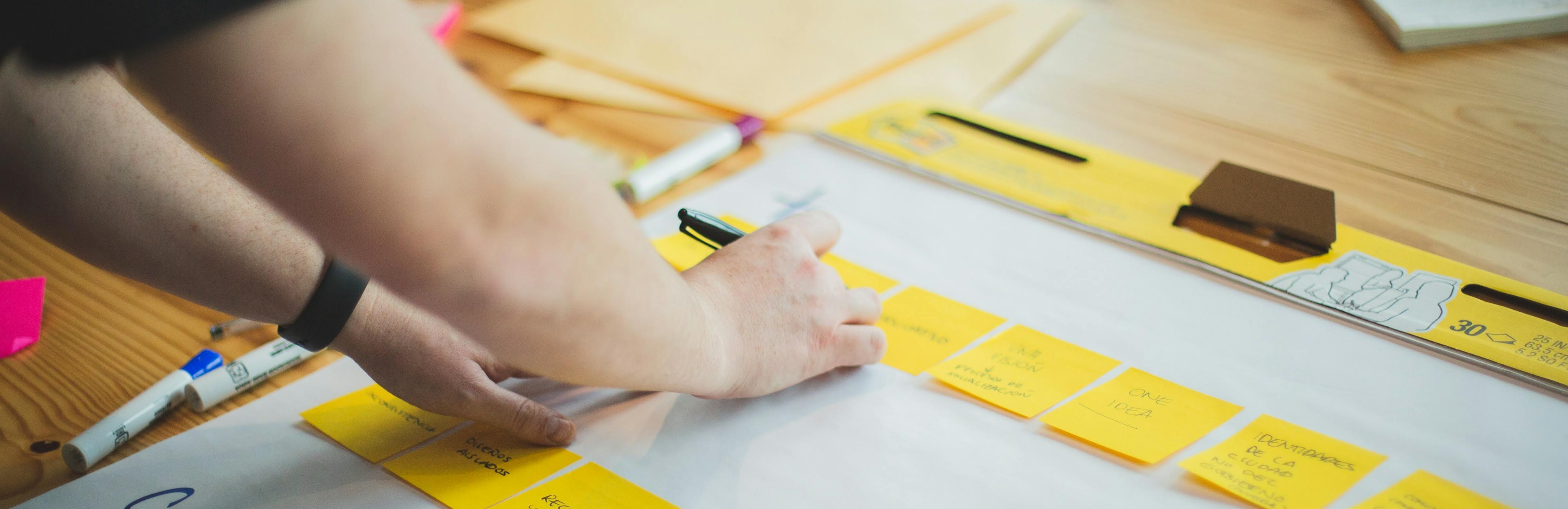 Person writing on post-its on a larger planning board