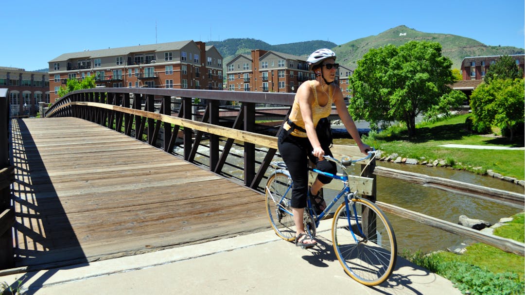 Woman rides her bike across a bridge in Golden.