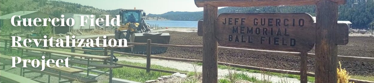 The Jeff Guercio Memorial Ball Field Sign in the foreground, behind it the Parks Department tills the field