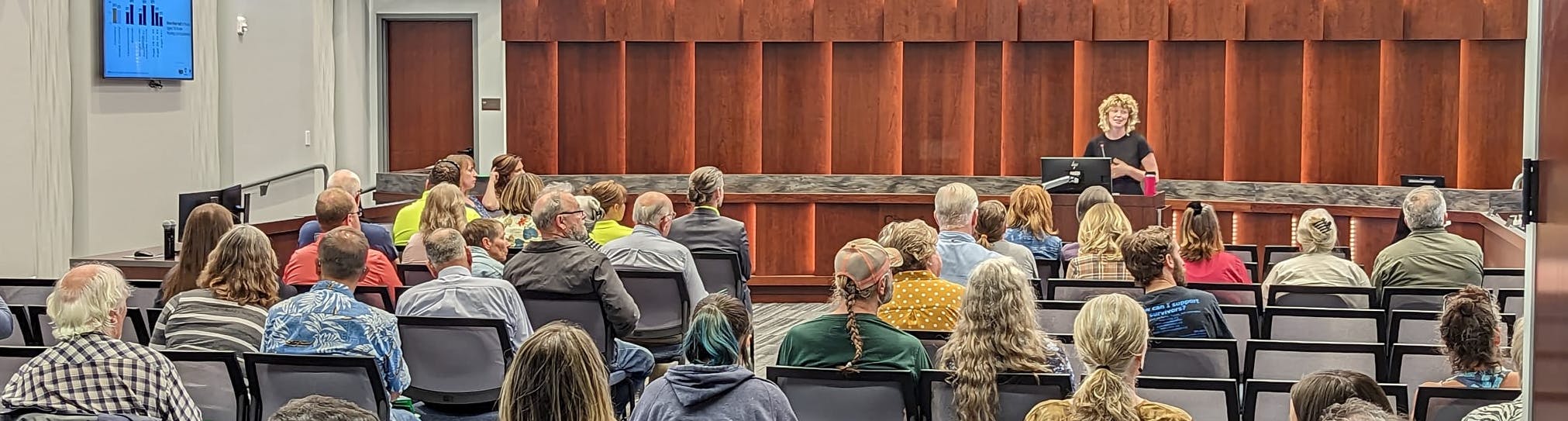 A group of people watching a presentation about housing insecurity