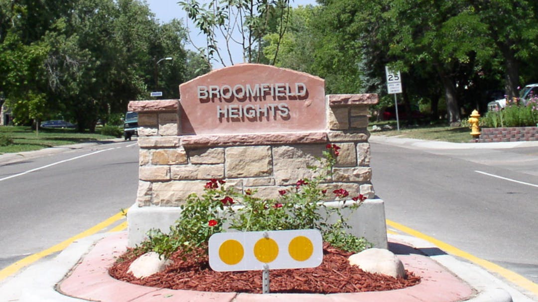 Monument sign with "Broomfield Heights" text located in street median. 