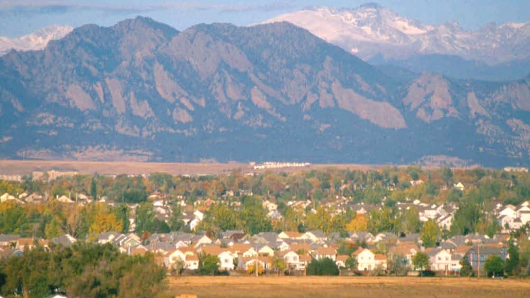 View of the Boulder Flatirons beyond a neighborhood.