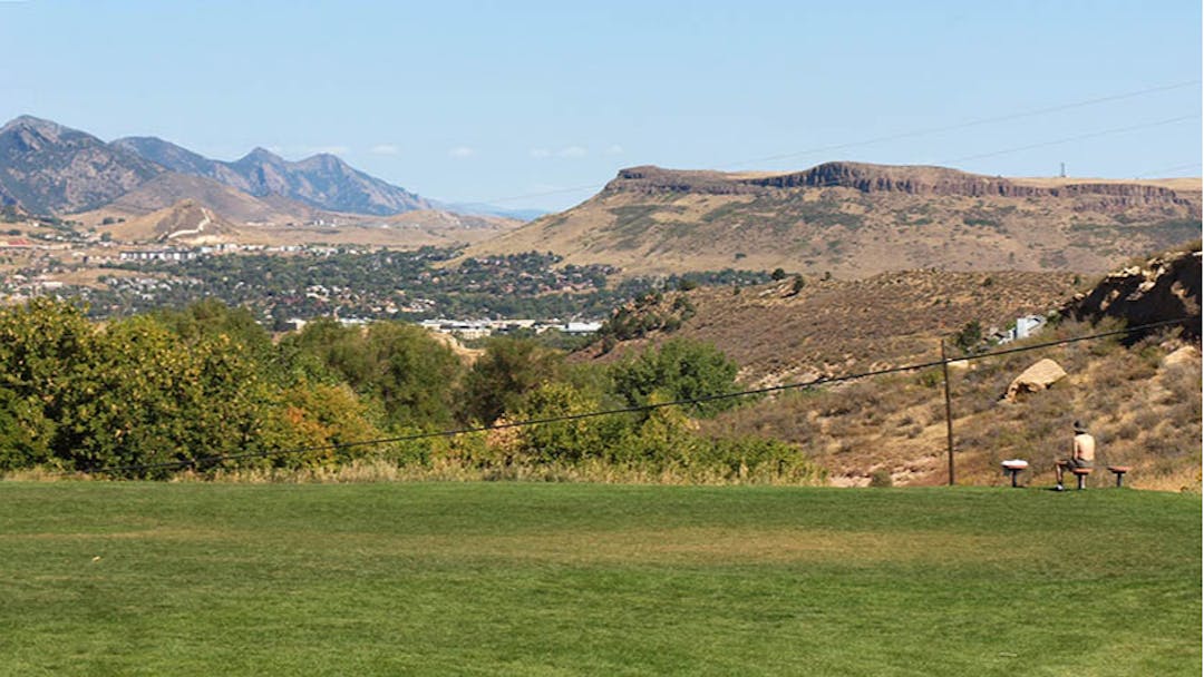 Panoramic view of Heritage Dells Park in summer with a person sitting on a park bench.