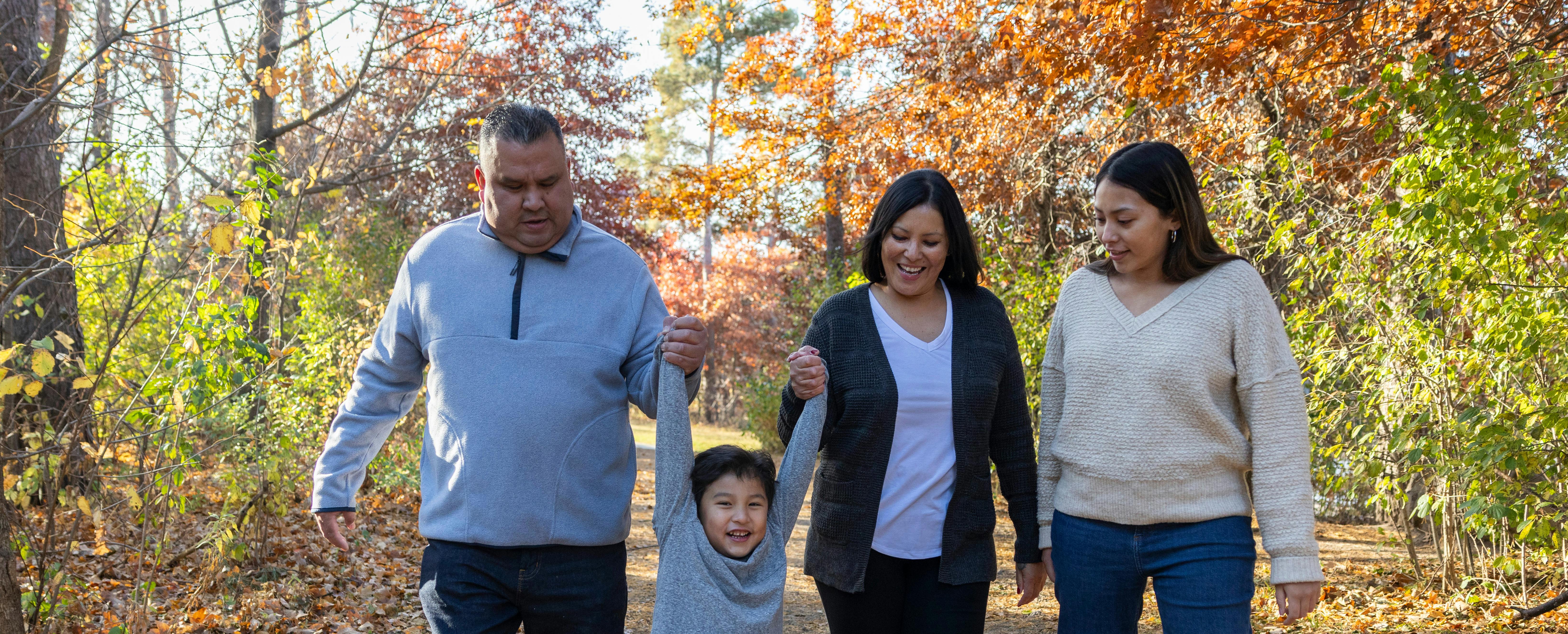 Family walking through the woods holding hand on a bright fall day. 