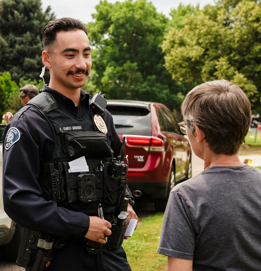 Lakewood Police agent speaks to resident beside patrol car