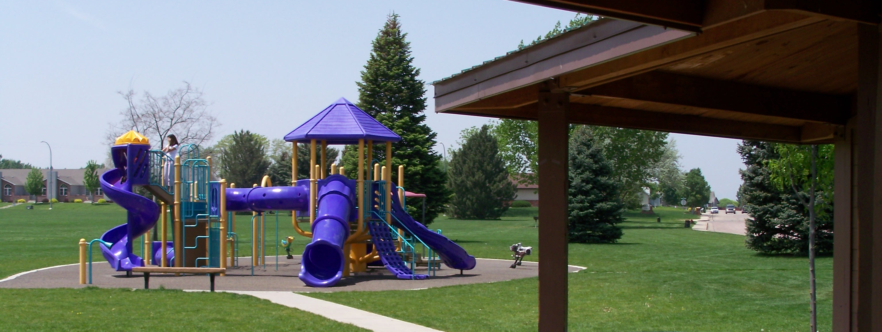 A purple playground with slides surrounded by grass in a park