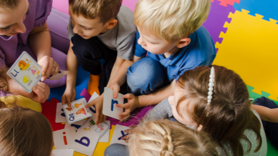 Children sitting on the floor, gathered around a child care provider