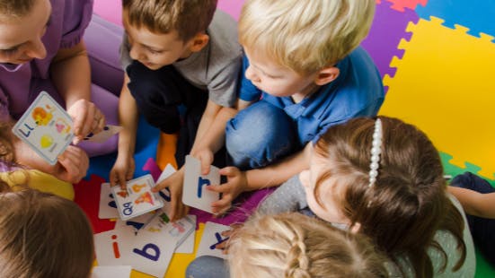 Children sitting on the floor, gathered around a child care provider