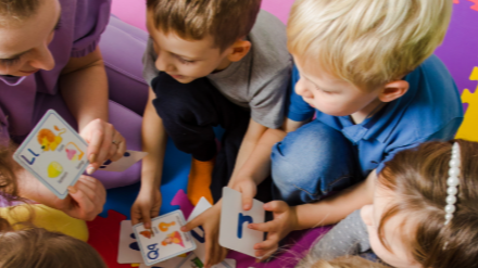 Children sitting on the floor, gathered around a child care provider
