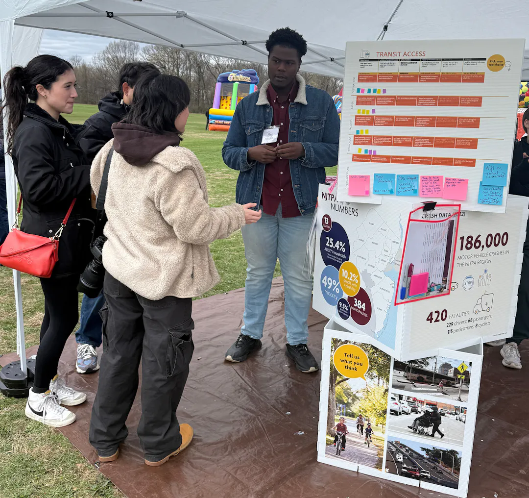 A staff member collects feedback from three people at a pop-up outreach event.