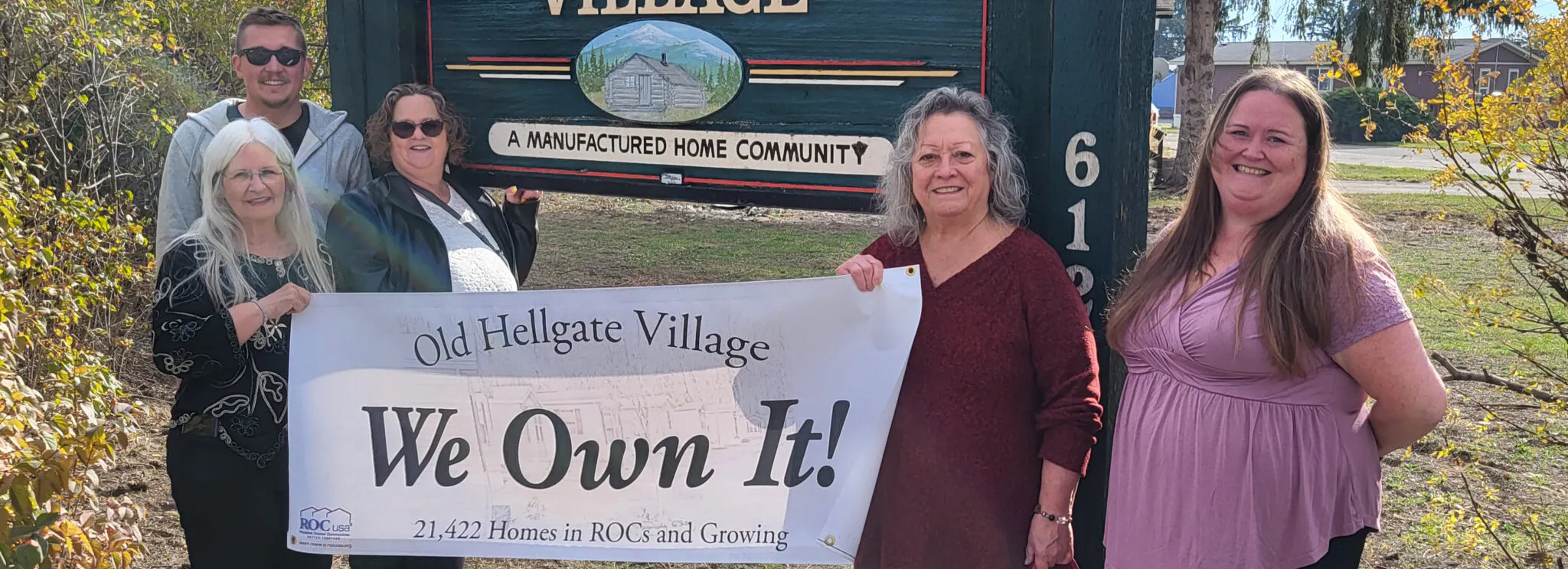 Five people in front of a wood sign that says Old Hellgate Village.