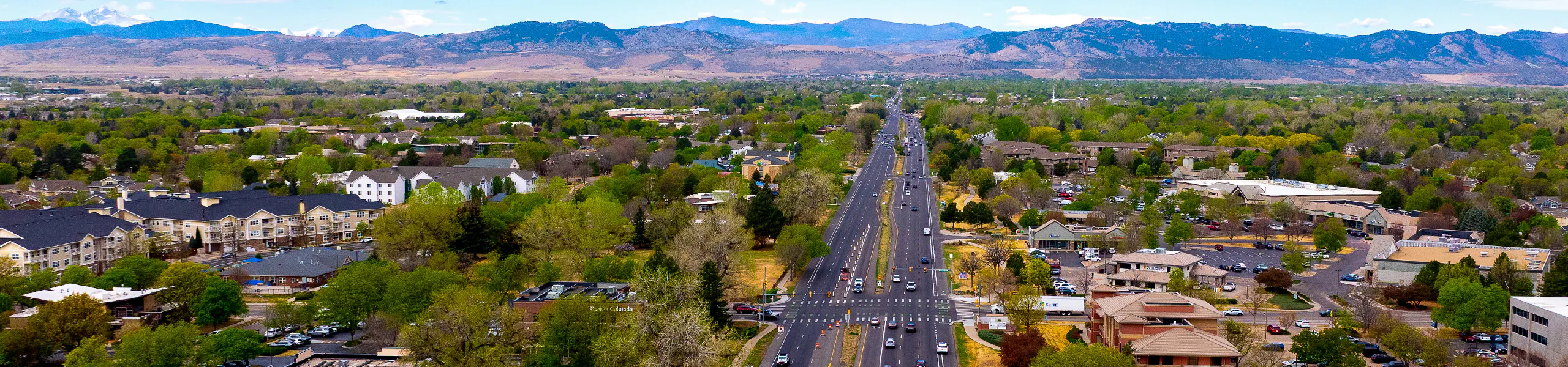 Aerial view of Fort Collins including streets, buildings, trees and the foothills in the distance