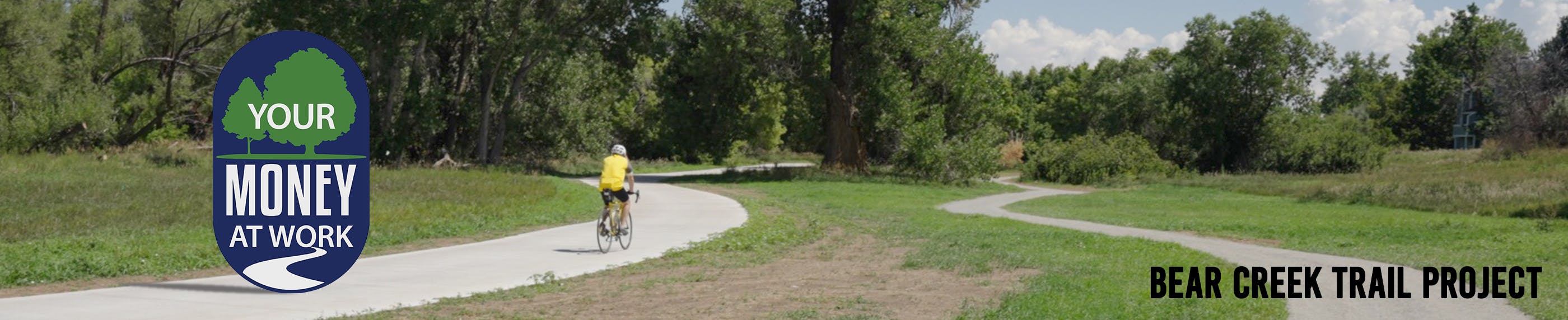 Bicyclist riding on Bear Creek Trail, and the new soft-surface trail for other users is to the right of cyclist. 
