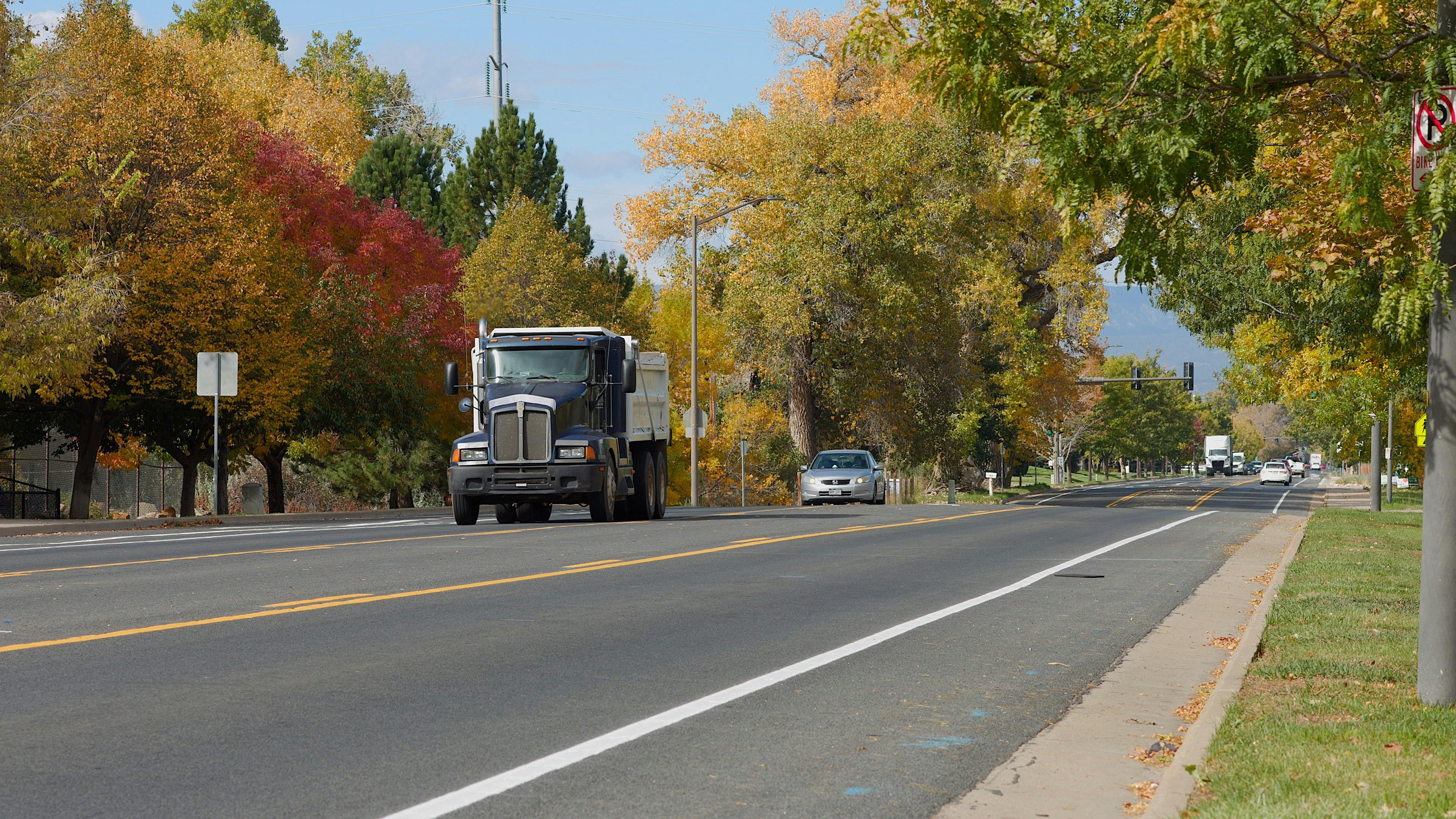 Ground level view of 1st Street with minimal traffic and fall leaves on the trees in the background.